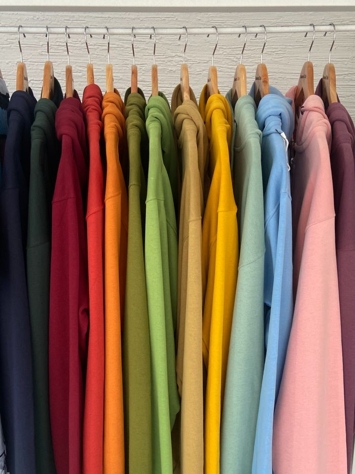 creative-03 A row of bright hoodies neatly hung in a closet, showcasing a rainbow of colors.