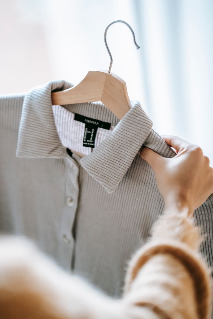creative-03 Crop anonymous female designer holding wooden hanger with elegant shirt while preparing for fashion event